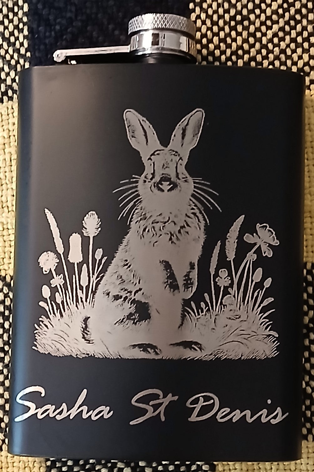 An engraved black flask with a bunny amongst flowers