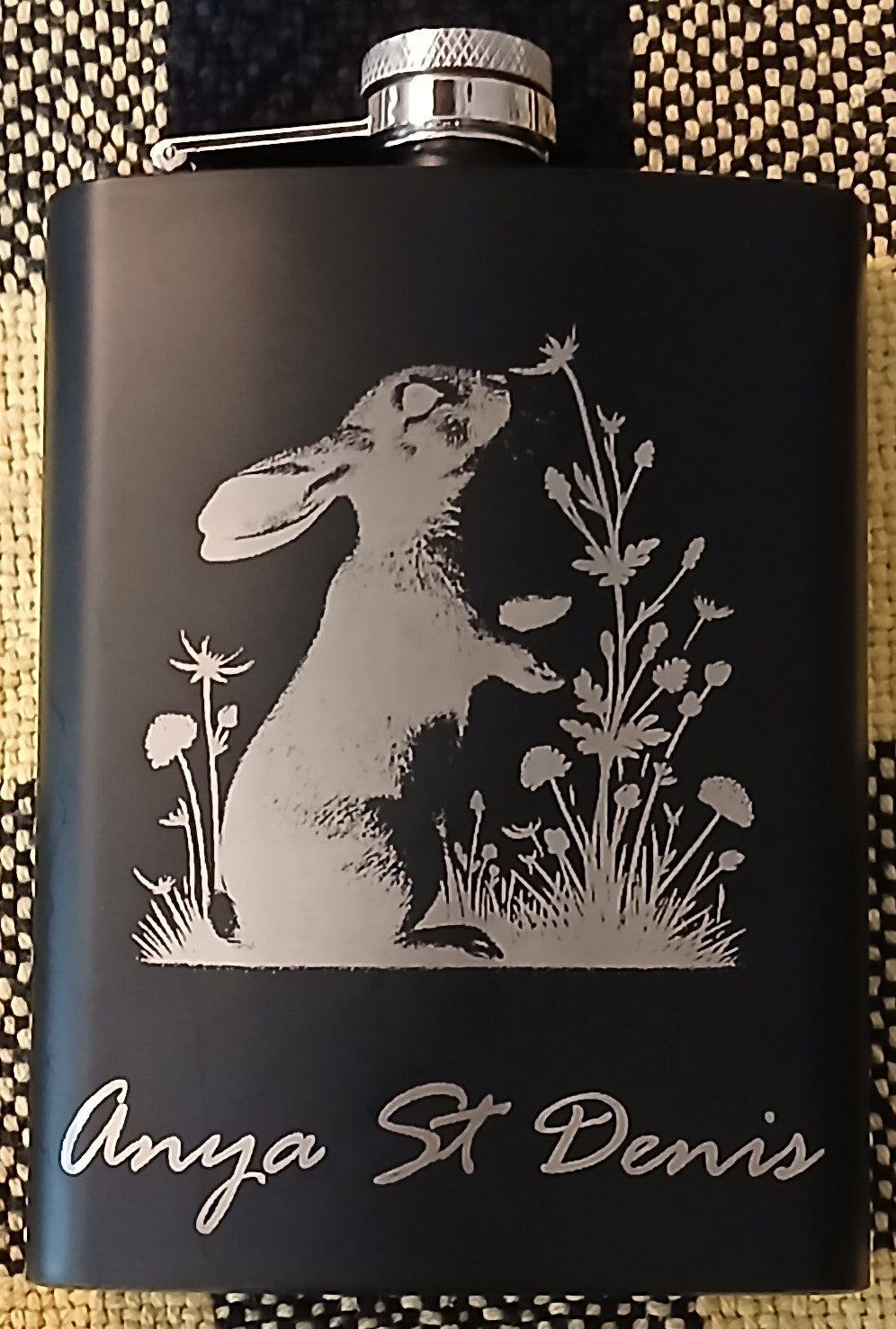 An engraved flask with a bunny smelling a flower