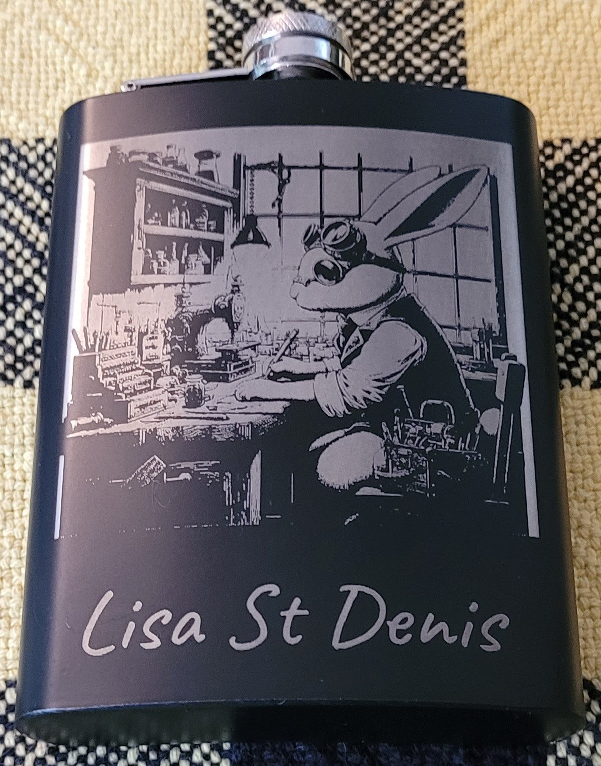 A black flask with an engraved image of a bunny tinkerer.