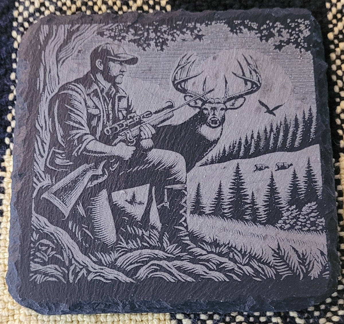 Decorative stone with a hunting scene engraved on it, featuring a hunter and deer in a forest setting.