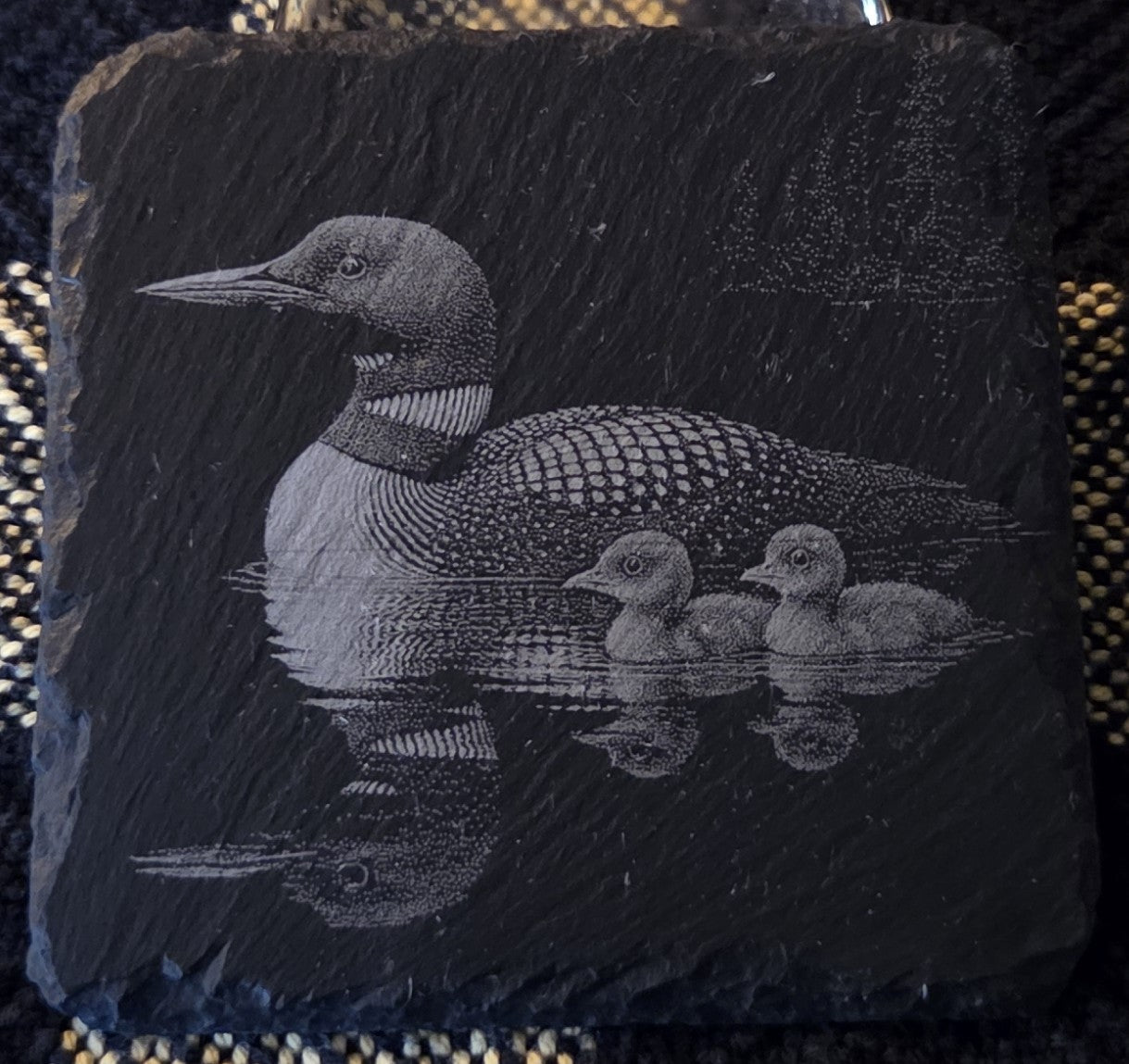 Slate coaster with engraved image of a loon and two loonettes on water